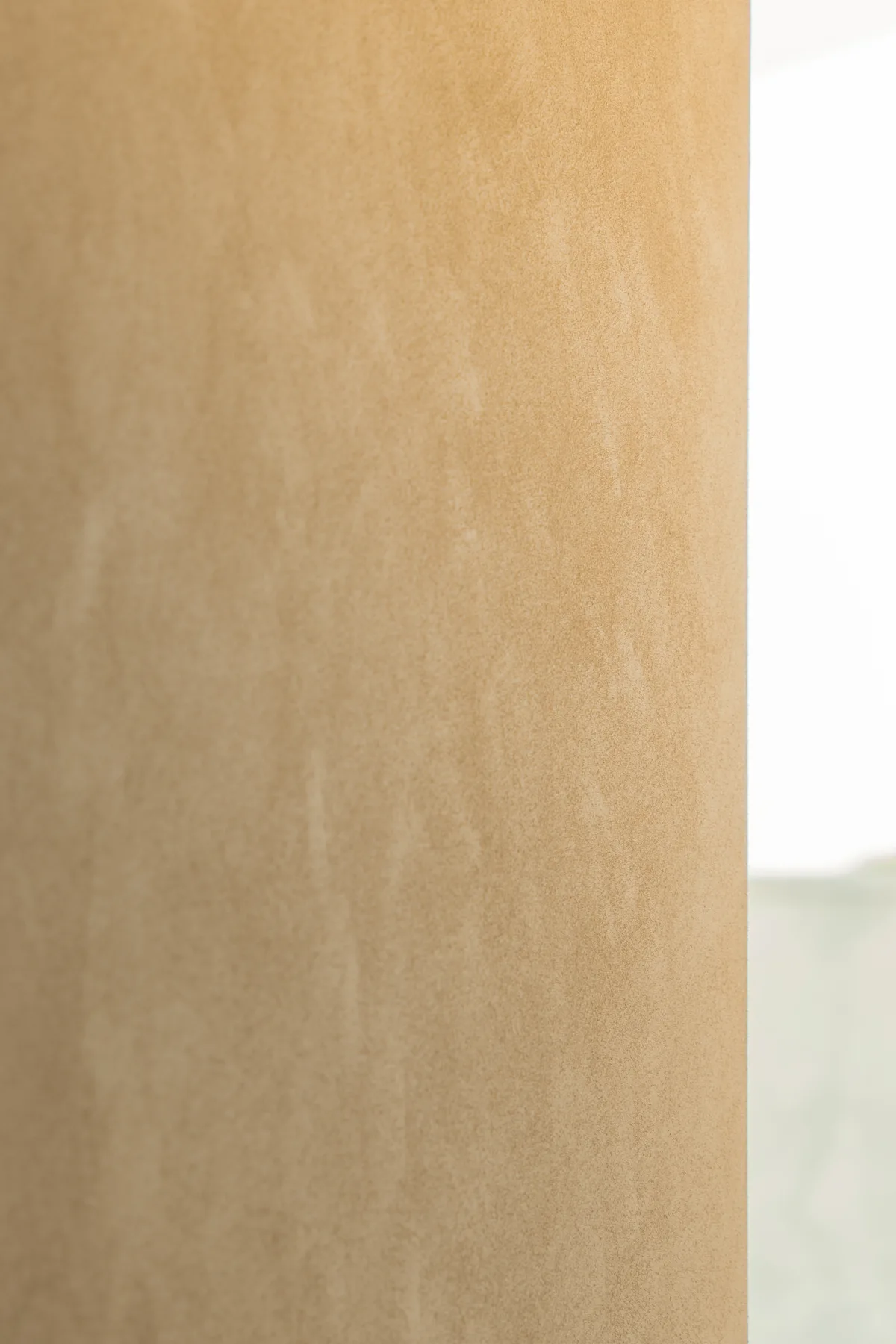 Warm neutral interior wall finish beside a window